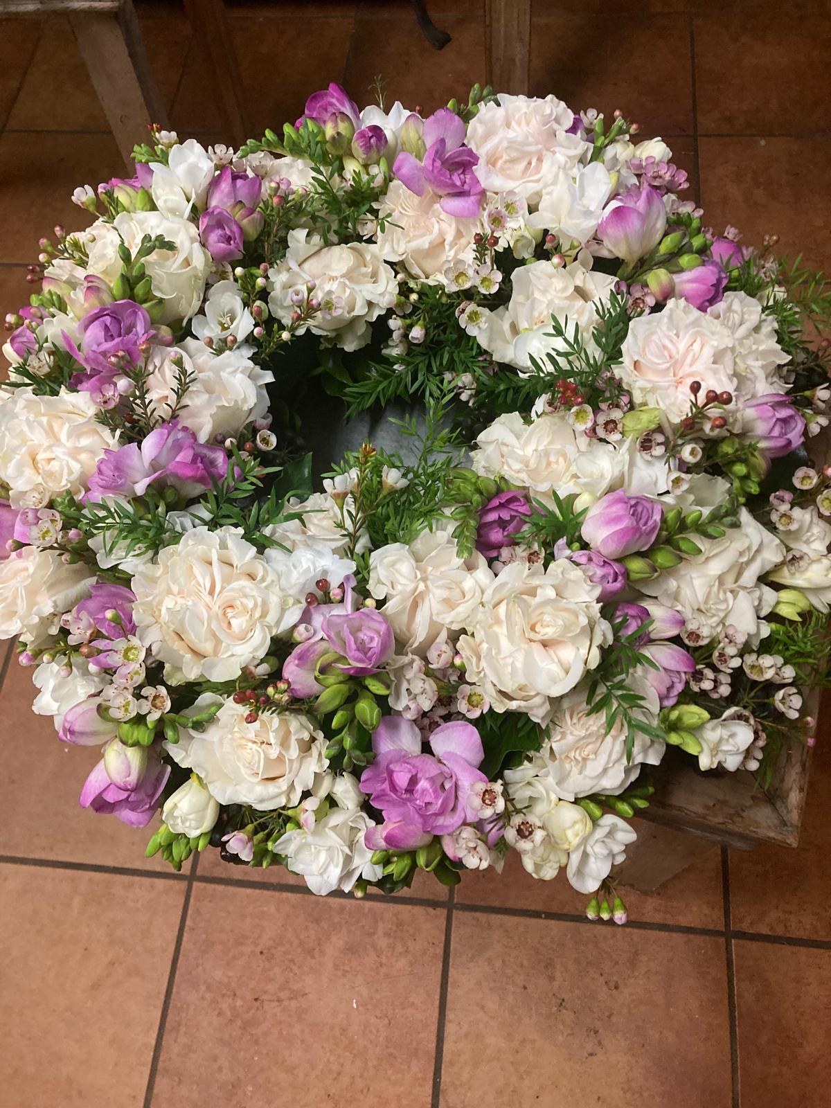 Trauerkranz mit weißen Rosen und lila Freesien